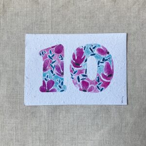 Carte représentant le numéro 10 illustré à l'aquarelle avec un motif floral fuchsia et tirquoise